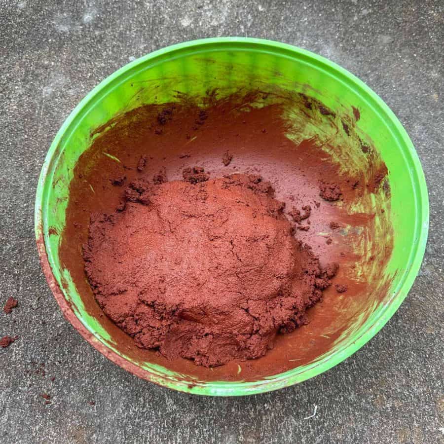 Bright red wet concrete mix in a bowl. Mix is in a dry mud pie shape.