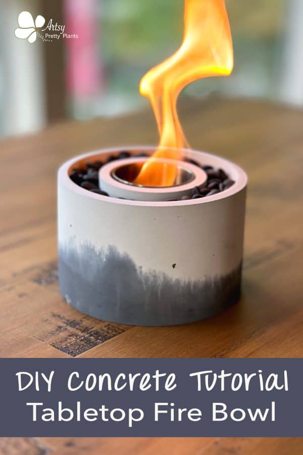 a black ad white marbled-looking concrete bowl on a tabletop with a flame coming out of it, sitting on a table outside. Text says Easy DIY concrete tabletop fire bowl.