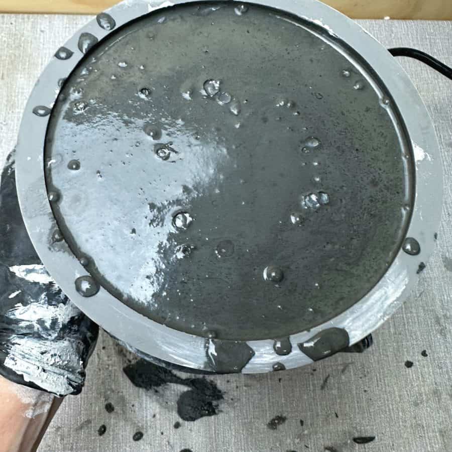 Air bubbles at the surface of the concrete mix inside a fire bowl silicone mold.