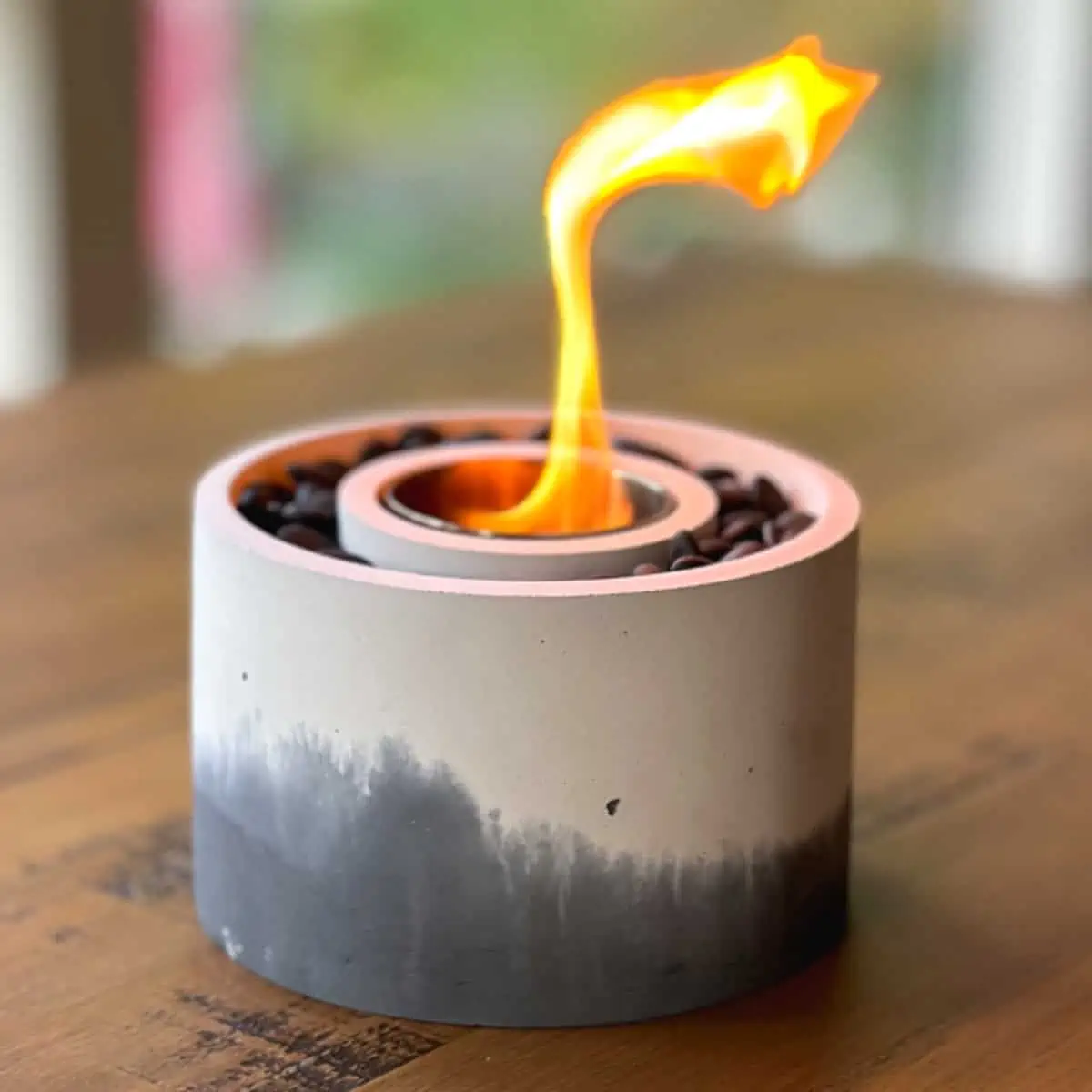 a black ad white marbled-looking concrete bowl on a tabletop with a flame coming out of it, sitting on a table outside.