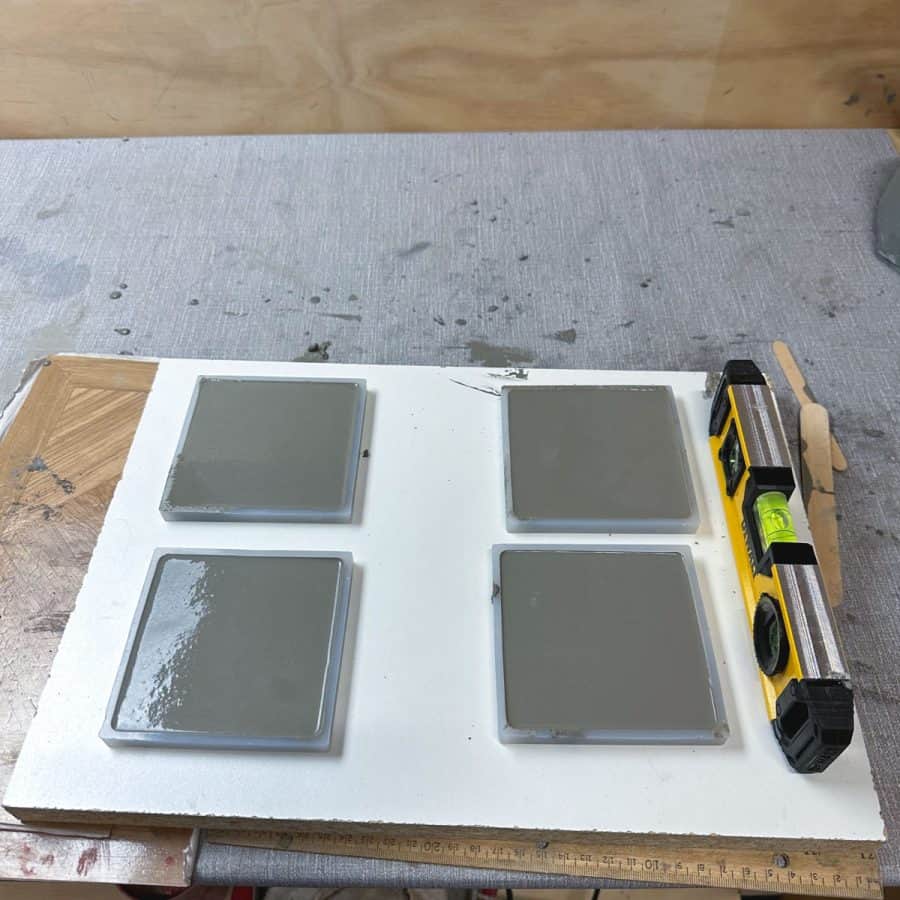 4 tile molds filled with concrete, on a board with a level.