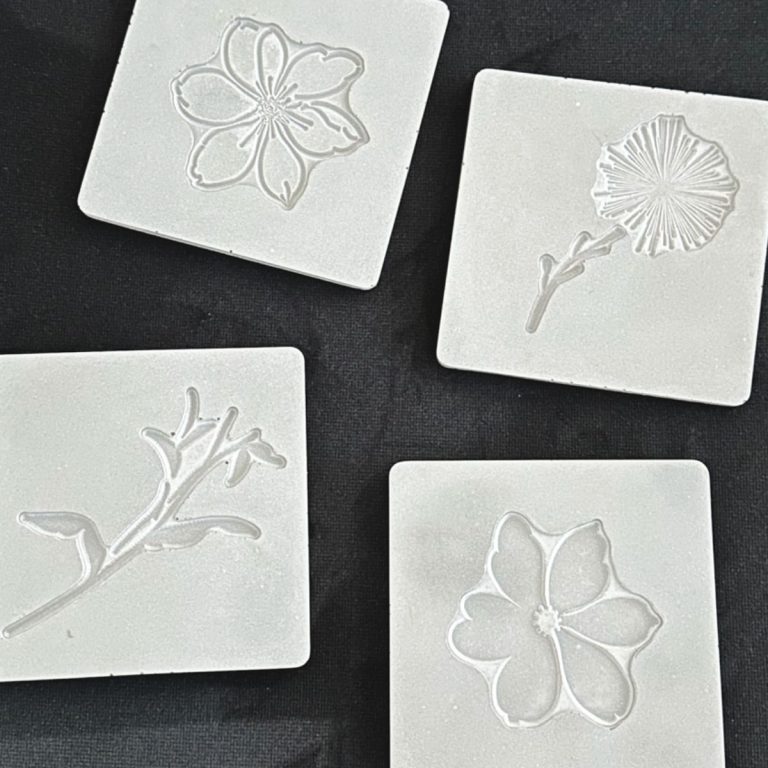 4 concrete tiles, unfilled with inlay designs made with easy silicone stamps.
