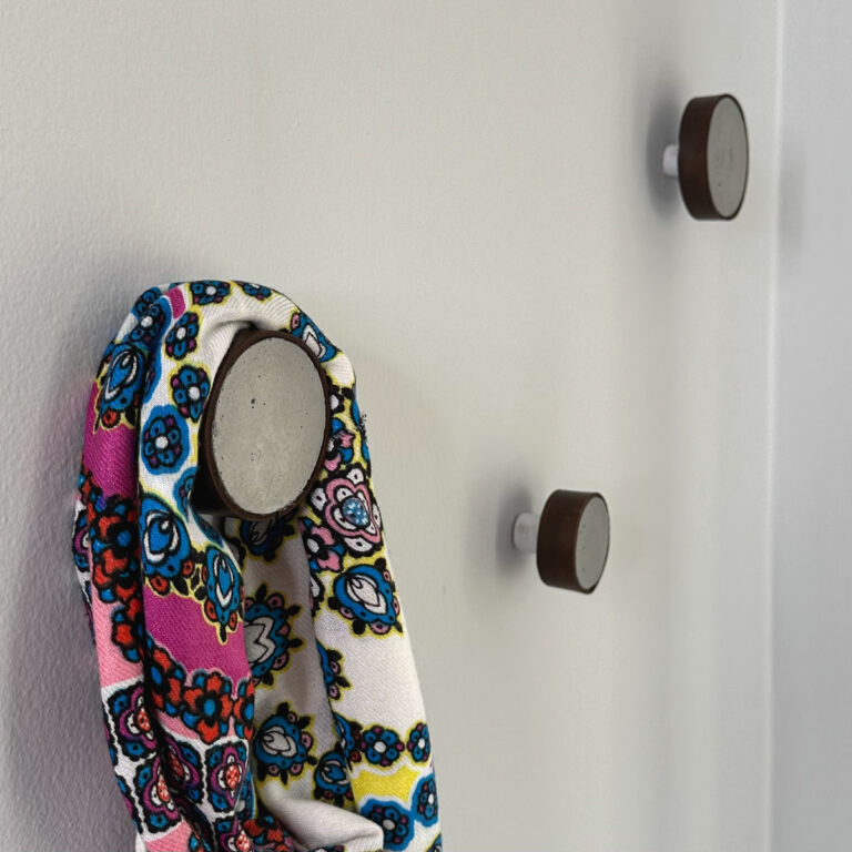 3 round hooks made out of cement and wrapped with leather, hanging on a wall.