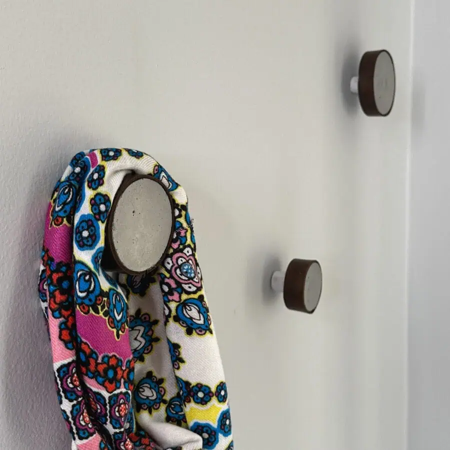 3 round hooks made out of cement and wrapped with leather, hanging on a wall.